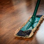 A detailed view of a mop cleaning a wooden floor, showing texture and pattern.