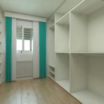 Spacious and modern minimalist wardrobe room with shelves and natural light.